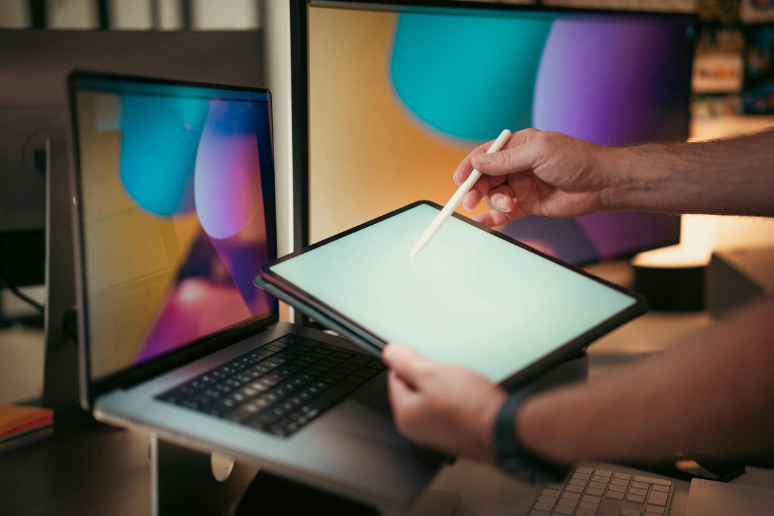 Main utilisant une tablette devant un écran d’ordinateur pour ajuster un site web